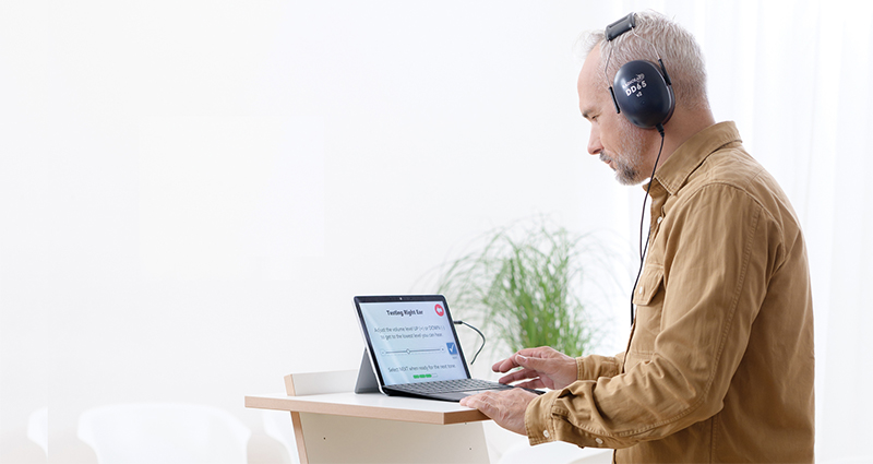 A man is taking a hearing screening using the tablet-only version of the medrx Kiosk